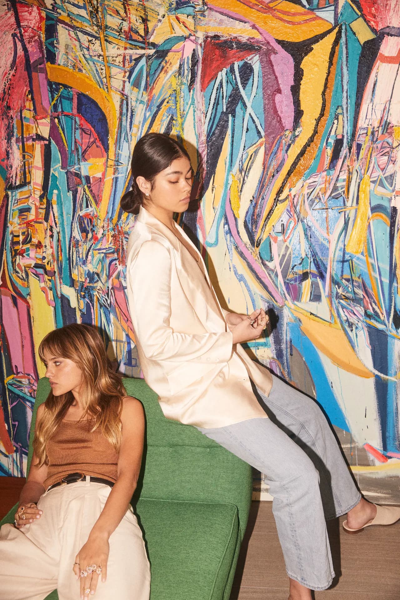 Two woman sitting in front of a painting in a studio wearing Heidi Gibson rings