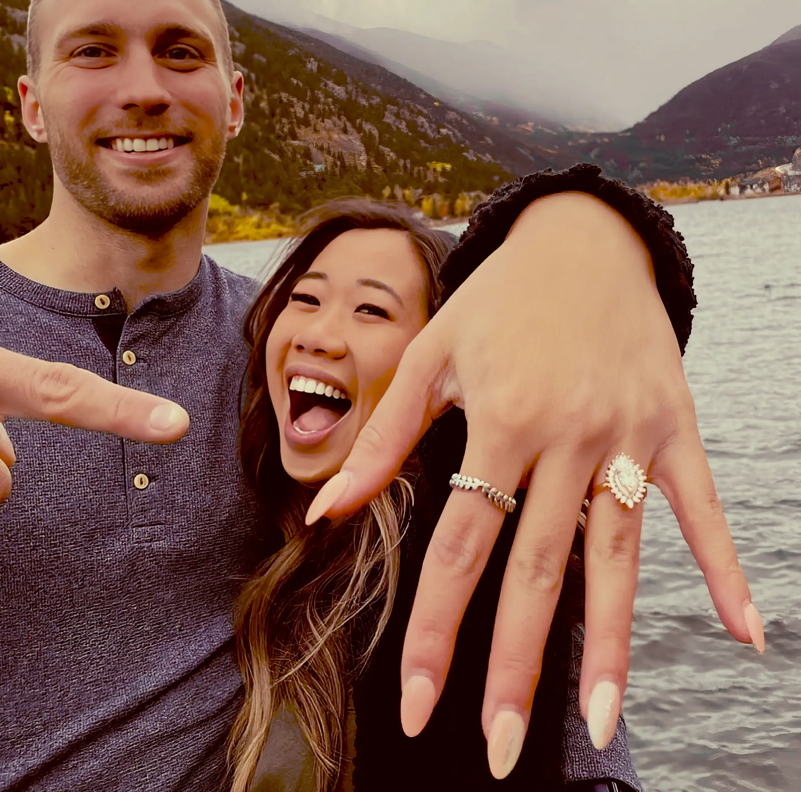 A man and a woman newly engaged pointing to their Heidi Gibson ring