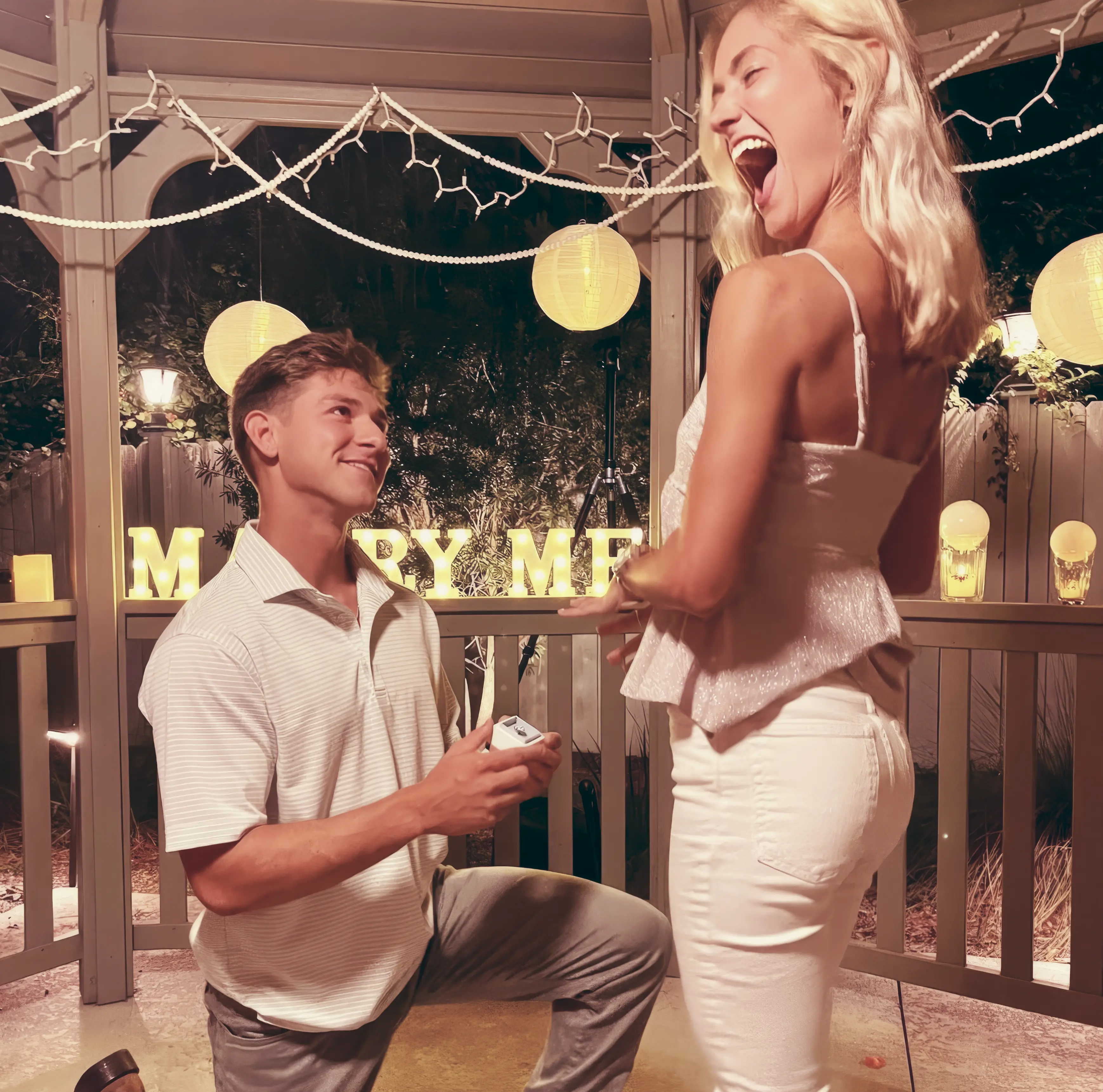 A man down on one knee proposing to he girlfriend with a Heidi Gibson ring